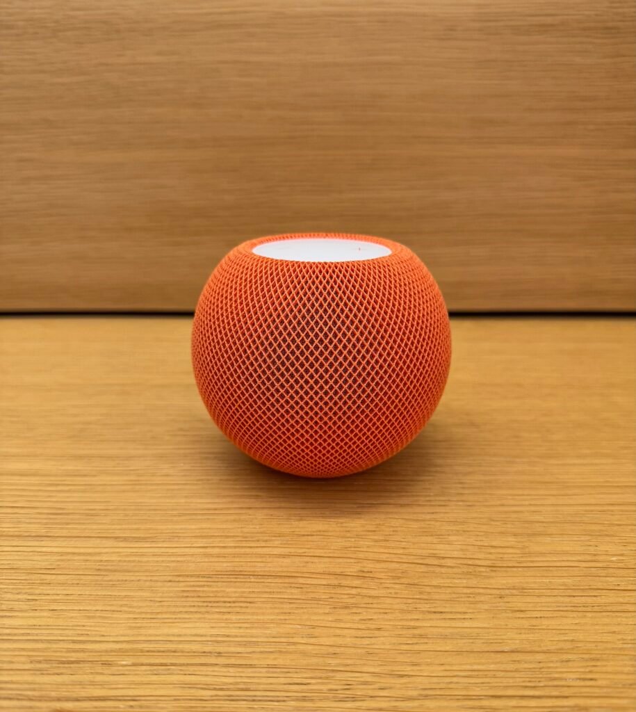 HomePod mini de Apple color naranja sobre una mesa de madera