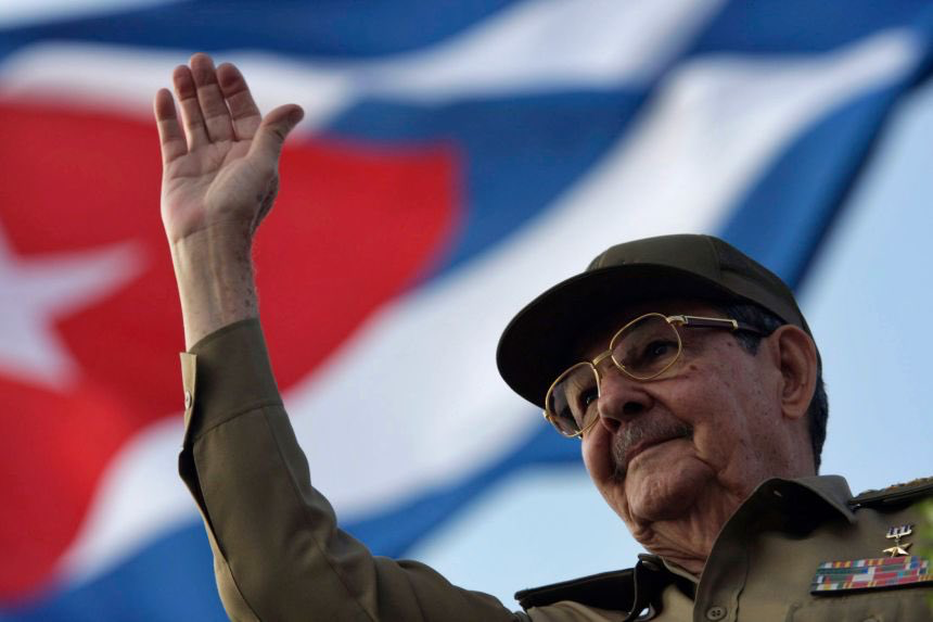Raúl Castro saluda frente a la bandera de Cuba